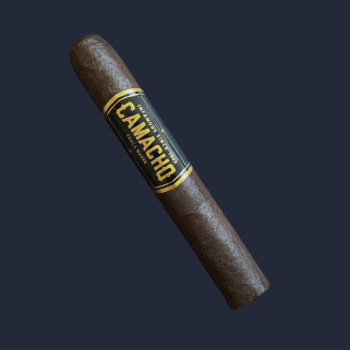 A Camacho Triple Maduro Robusto in dark San Andrés wrapper, banded in black and gold, against a navy backdrop.