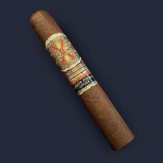 A Fuente Fuente OpusX with its ornate red, gold and black crest band, tapered head resting against navy.