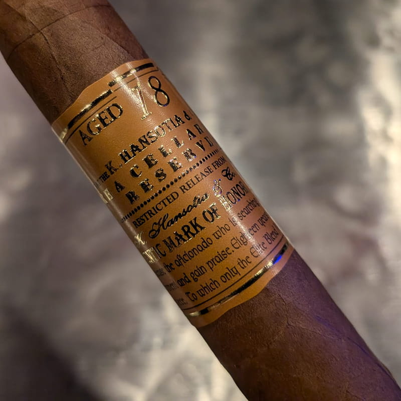 A pale Connecticut-shade Gurkha Cellar Reserve cigar with a tall cream and gold band reading Aged 18 Years, K. Hansotia and Co.